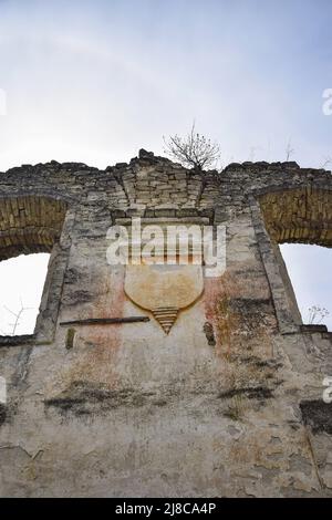 Religiöses Symbol. Ruinen einer alten Synagoge mit Bogenfenstern, gegen den blauen Himmel. Texture altes verfallenen Mauerwerk. Baum wächst an der Wand. Stockfoto