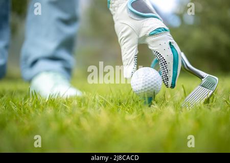 Hand in Hand platzieren Golfball auf T-Stück Stockfoto