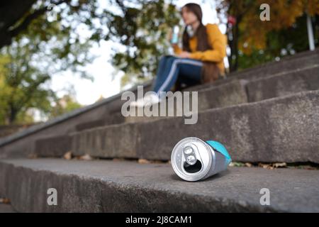 Eine gequetschte Aluminiumbüste und ein Teenager, der auf der Treppe Energie trinkt. Stockfoto