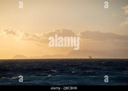 Himmel und Meer bei Sonnenuntergang und ein weit entfernes Schiff Stockfoto