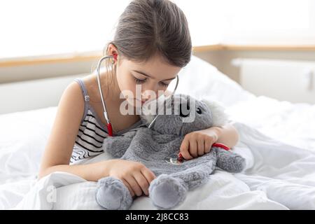 Glückliches kleines Mädchen mit weichem Spielzeug Koala im Bett. Stockfoto