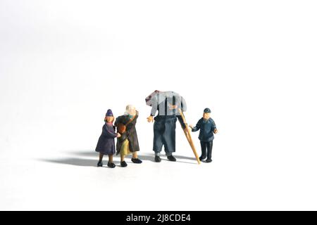 Miniatur Menschen Spielzeug Figur Fotografie. Eine Gruppe von armen Familiengroßvater, Oma und zwei Enkelkindern auf weißem Hintergrund isoliert. Bildfoto Stockfoto