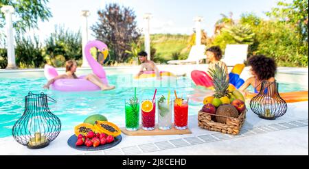Sommerschwimmbad-Party! Glückliche multirassische Gruppe von Freunden, die sich auf aufblasbarer Matratze mit Getränken entspannen, die heiße Feiertage im Freien feiern Stockfoto