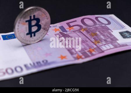 500-Euro-Banknote mit entkoffter Silber-Bitcoin-Münze lag darüber. 500 Euro Banknote mit Silberbitcoin in defokussiert und perspektivisch. Stockfoto