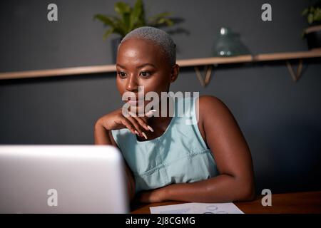 Eine junge schwarze Geschäftsfrau arbeitet spät in der Nacht vor ihrem Laptop Stockfoto