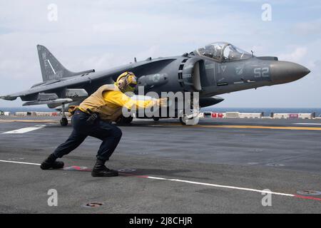 US Navy Aviation Boatswains Mate 3. Class Alissa Sanchez signalisiert einem Marine Corps AV-8B Harrier, der an das Schwarze Schaf der Marine Attack Squadron 214 befestigt ist, vom Flugdeck des amphibischen Sturmschiffs USS Essex der Wasp-Klasse am 14. Januar 2022 auf dem Südchinesischen Meer zu starten. Stockfoto
