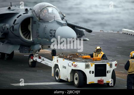 Die Besatzung des Flugdecks der US Navy schleppt einen Marine Corps AV-8B Harrier, der an die 22. Marine Expeditionary Unit angeschlossen ist, um auf dem Flugdeck des amphibischen Sturmschiffs USS Kearsarge der Wasp-Klasse am 20. April 2022 auf dem Atlantischen Ozean zu starten. Stockfoto