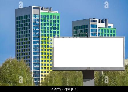 Plakatwand-Mockup im Freien, leere weiße Plakatwand. Hintergrund von Hochhäusern. Plakat für Außenwerbung auf der Straße. Stockfoto