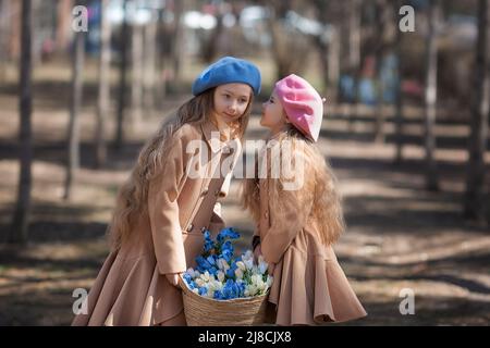 Zwei Mädchen Schwestern Kinder geht durch den Wald im Frühjahr und sammelt die ersten Frühlingsblumen in Korb . Stockfoto