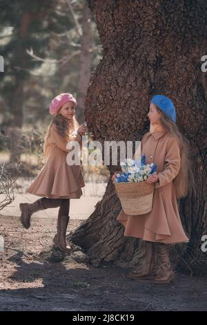 Zwei Mädchen Schwestern Kinder geht durch den Wald im Frühjahr und sammelt die ersten Frühlingsblumen in Korb . Stockfoto