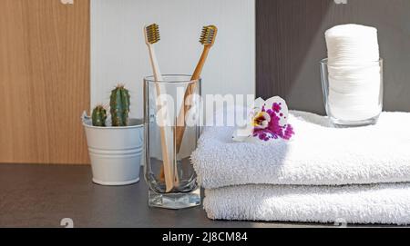 Badezimmerausstattung, Bürsten für die Mundhygiene und Baumwollhandtücher auf grauem Hintergrund. Stockfoto