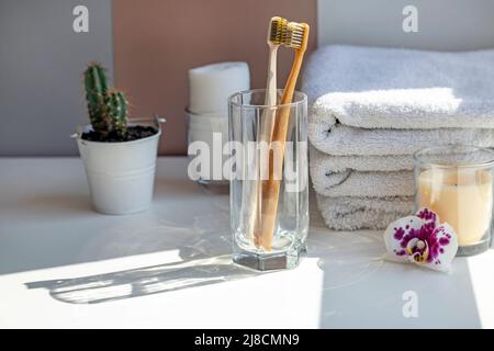 Zwei keramische Zahnbürsten Klammern sich aneinander, blendendes Licht von der Sonne auf einem weißen Tisch im Badezimmer, der Morgensonne. Stockfoto