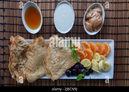 Gesundes Frühstück mit Pfannkuchen. Hausgemachte amerikanische Pfannkuchen mit Obst, Beeren und Honig. Draufsicht flach lag . Stockfoto