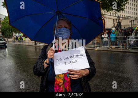 Whitehall, Westminster, London, Großbritannien. 15.. Mai 2022. Im Regen vor der Downing Street in Whitehall findet ein Protest gegen angebliche Lügen, Inkompetenz und Korruption des Premierministers Boris Johnson und der konservativen Regierung statt. Die Demonstranten sind wütend auf die Bilanz der Regierung in Bezug auf den Brexit, die Covid-Pandemie und die Lebenshaltungskrise und fordern Johnsons Rücktritt und höhere Standards von den Abgeordneten. Maskierte Hündin mit Banana republic Britain Zeichen Stockfoto