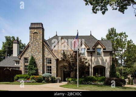 Rustikales, gehobenes, aus Stein und Backsteinen gewachsenes, wunderschön gestaltetes Haus mit Kupferspitzen und Kaminabdeckungen, die amerikanische Flagge auf dem hohen Fahnenmast vor dem Hof führen Stockfoto