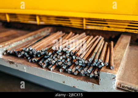 Stifte aus Metallverstärkung liegen in der Werkstatt auf der Werkbank. Werkstück für Konstruktion oder gewalztes Metall. Industrieller Hintergrund. Stockfoto