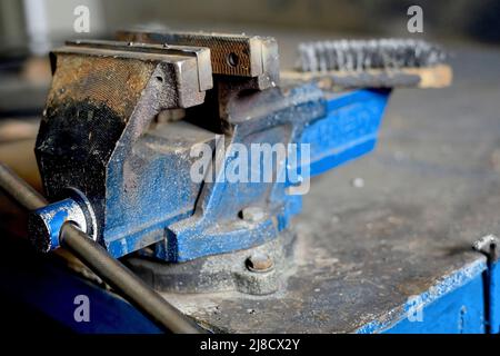 Metall-Werkbank mit Viskel zum Spannen von Teilen. Blick auf den Arbeitsplatz in der Werkstatt. Ordnung und Sauberkeit am Arbeitsplatz. Arbeitsschutz. Hintergrund Stockfoto