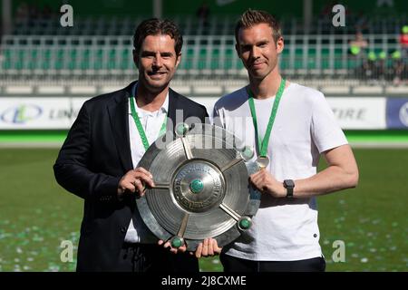 15. Mai 2022, Niedersachsen, Wolfsburg: Fußball: Bundesliga, VfL Wolfsburg - Bayer Leverkusen, Matchday 22, AOK-Stadion. Wolfskis Trainer Tommy Stroot (r) und Wolfskis Sportdirektor Ralf Kellermann posieren mit der Meisterschale. Foto: Swen Pförtner/dpa - WICHTIGER HINWEIS: Gemäß den Anforderungen der DFL Deutsche Fußball Liga und des DFB Deutscher Fußball-Bund ist es untersagt, im Stadion und/oder vom Spiel aufgenommene Fotos in Form von Sequenzbildern und/oder videoähnlichen Fotoserien zu verwenden oder zu verwenden. Stockfoto