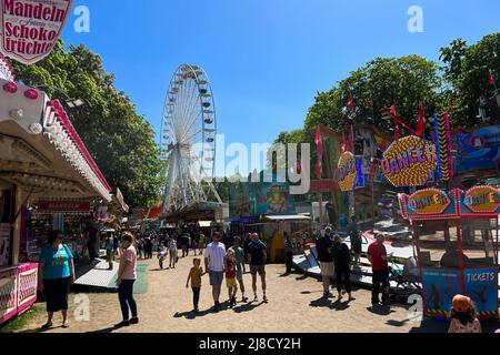 BERLIN, DEUTSCHLAND - 15. MAI 2022: Überfüllte Fun Fair, Karneval Neuköllner Maientage mit KARNEVALSREITÄNZERIN, Riesenrad Riesenrad und Concession Stan Stockfoto