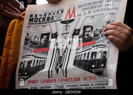 Moskau, Russland. 15.. Mai 2022. Die Zeitung Vechernaya Moskva 14. Mai 1935 Ausgabe mit Informationen über die Eröffnung der U-Bahn in Moskau. Park Kultury Station reenacts, an einer Straße vor einem Eingang zum Bahnhof, die Zeremonie 1935 zum Start der ersten Linie überhaupt, um den 87.. Geburtstag der Moskauer Metro, Russland zu feiern. Der rote Titel lautet „Grüße an die glorreichen Bauherren der U-Bahn“, Nikolay Vinokurov/Alamy Live News Stockfoto