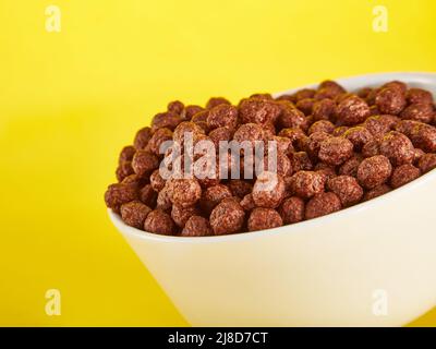 Schokoladen-Maiskugeln in Schale auf gelbem Hintergrund Stockfoto