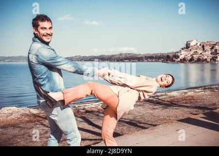 Das junge Paar tanzt und hat Spaß am Ufer des Lago Bracciano in Italien. Ein Paar reist nach Anguillara Sabazia, einem wunderschönen italienischen Dorf. Stockfoto