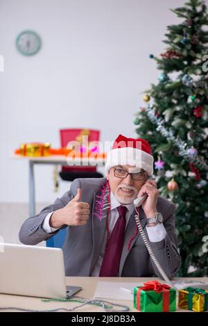 Ein alter Geschäftsmann feiert Weihnachten im Büro Stockfoto