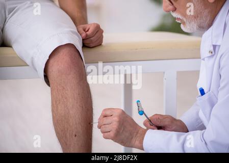 Junger Patient besucht alten männlichen Arzt Neurologe Stockfoto