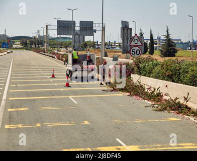 Larnaca, Zypern - 31. Mai 2021: Bushschneidstraße arbeitet auf der Autobahn zum Flughafen Larnaca. Larnaca ist nach Nikosia die drittgrößte Stadt des Landes Stockfoto