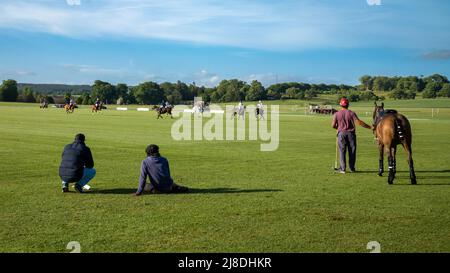 Zwei stabile Hände und ein Bräutigam mit einem Ersatzpferd beobachten ein Polospiel im Cowdray Park, West Sussex, England. Stockfoto