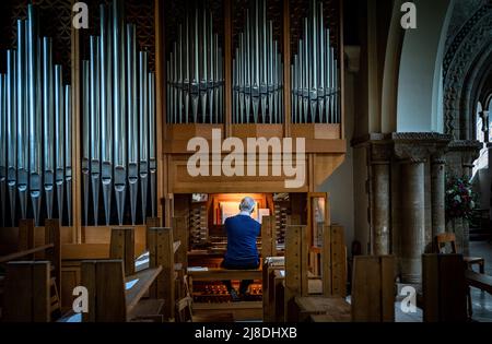 Ein Organist spielt allein in der leeren St. Peter's Church in Petersfield, Hampshire, England Stockfoto