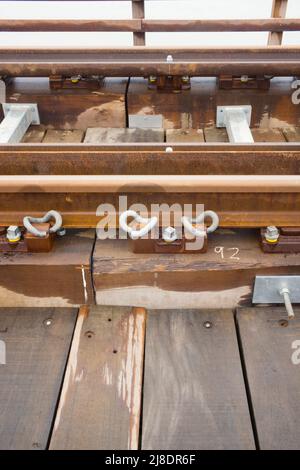 Nahaufnahme einer Stahleisenbahn mit Pandrol E-Clip auf der neu modernisierten Barmouth-Eisenbahnbrücke Stockfoto