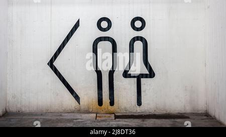 WC-Schild mit männlichen und weiblichen Anstrich an einer Betonwand. Stockfoto