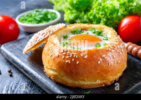 In einem Brötchen gebackenes Ei mit Schinken, Käse und Kräutern. Französisches Frühstück. Gesunde Ernährung Konzept Stockfoto