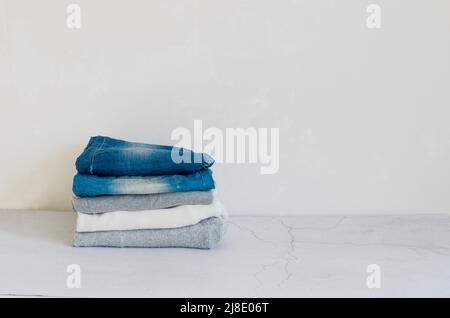 Pullover und blaue Jeans auf grauem Hintergrund, Bügeln, Wäsche, Komfort für zu Hause, Textil, Gestrickt, Damenbekleidung, Baumwolle, lässige Stockfoto