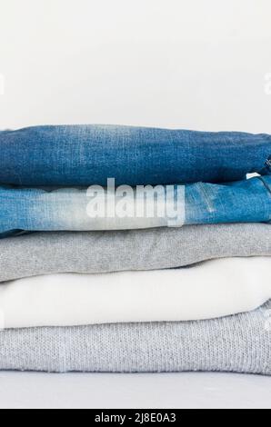 Pullover und blaue Jeans auf grauem Hintergrund, Bügeln, Wäsche, Komfort für zu Hause, Textil, Gestrickt, Damenbekleidung, Baumwolle, lässige Stockfoto