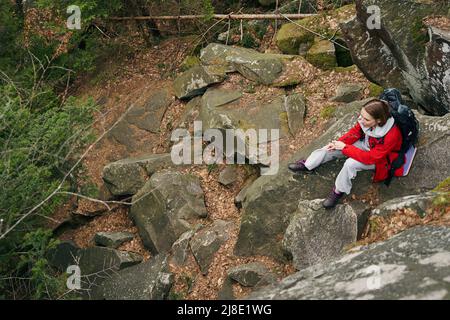 Dame, die auf einem Spaziergang eine Pause auf Stein gemacht hat Stockfoto