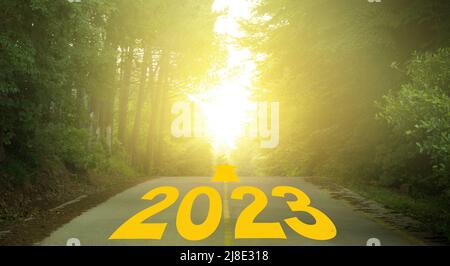 Wort 2023 geschrieben auf bewaldeten Landstraße. Konzept für das neue Jahr 2023. Jubiläumsbanner für Ziel-, Erfolg- und Motivationskonzepte Stockfoto