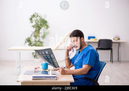 Junger Radiologe, der in der Klinik sitzt Stockfoto