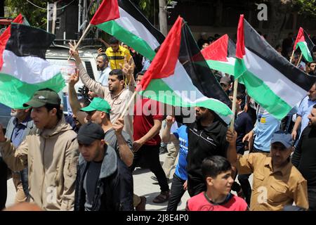 Gaza-Stadt, Palästina. 15. Mai 2022. Die Palästinenser schwenken ihre Nationalflaggen während einer Kundgebung zum 74h. Jahrestag dessen, was die Palästinenser die "Nakba" nennen, oder "Katastrophe", die sich auf ihre Entwurzelung im Krieg um die Gründung Israels im Jahr 1948 bezieht, vor den UNESCO-Büros in Gaza-Stadt. Kredit: Majority World CIC/Alamy Live Nachrichten Stockfoto