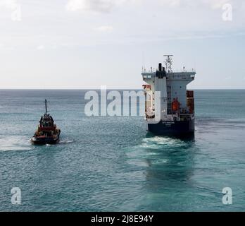 Bridgetown, Barbados - 26. März 2022: Das Frachtschiff CFS Horizon verlässt den Hafen von Bridgetown, begleitet von einem Schlepper, wie aus der Sicht Stockfoto