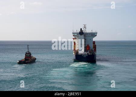 Bridgetown, Barbados - 26. März 2022: Das Frachtschiff CFS Horizon verlässt den Hafen von Bridgetown, begleitet von einem Schlepper, wie aus der Sicht Stockfoto