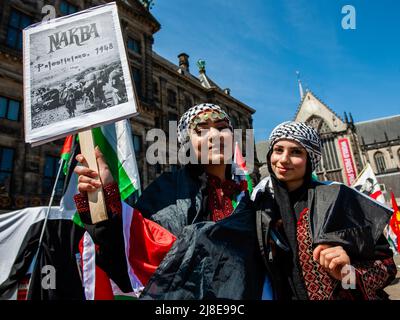 Palästinensische Frauen in traditioneller Kleidung werden bei einer Kundgebung zum 74.. Jahrestag des Nakba-Tages auf dem Dam-Platz in Amsterdam mit einem Plakat gesehen. Palästinensische Demonstranten versammelten sich anlässlich des 74.. Jahrestages des Nakba-Tages auf dem Dam-Platz in Amsterdam und verurteilten den Mord an dem palästinensisch-amerikanischen Journalisten Shireen Abu Aklei durch israelische Truppen. Das Wort „Nakba“ bedeutet auf Arabisch „Katastrophe“ und bezieht sich auf die systematische ethnische Säuberung von zwei Dritteln der palästinensischen Bevölkerung zu der Zeit durch zionistische Paramilitärs zwischen 1947-1949 und der nahezu gesamten d Stockfoto