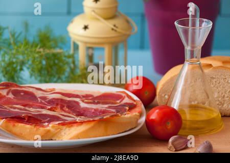 Brotteller mit Schinken, Knoblauch, Tomaten, Öl und Salz, gesundes Frühstück, Typisches Gericht Kataloniens und der mediterranen Küche. Stockfoto