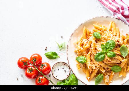 Italienische Pasta mit Tomatensauce, Basilikum und Parmesankäse auf weißem Tisch. Stockfoto