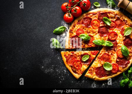 Traditionelle italienische Pizza mit Salami, Tomaten und Basilikum. Stockfoto