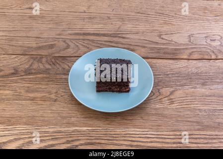 Portion Brownie mit Tod durch Schokolade auf blauem Teller und Holztisch Stockfoto