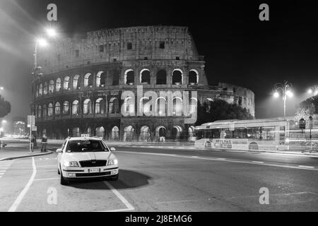 Rom, Italien - Januar 18. 2011: Taxi-Auto am Kolosseum in der Stadt Rom in der Nacht. Schwarzweiß-Fotografie Stockfoto