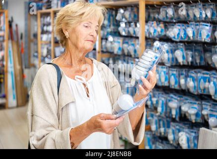 Ältere Frauen entscheiden sich im Baumarkt für eine Energiesparlampe Stockfoto