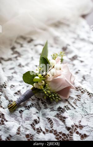 Hochzeit boutonniere liegt auf einem beigen Spitzenkleid. Stockfoto
